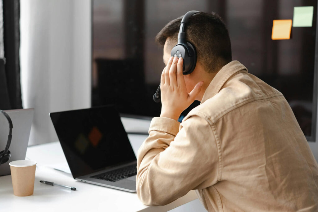 Persona in difficoltà davanti a un laptop con schermo nero, simbolo di perdita dati