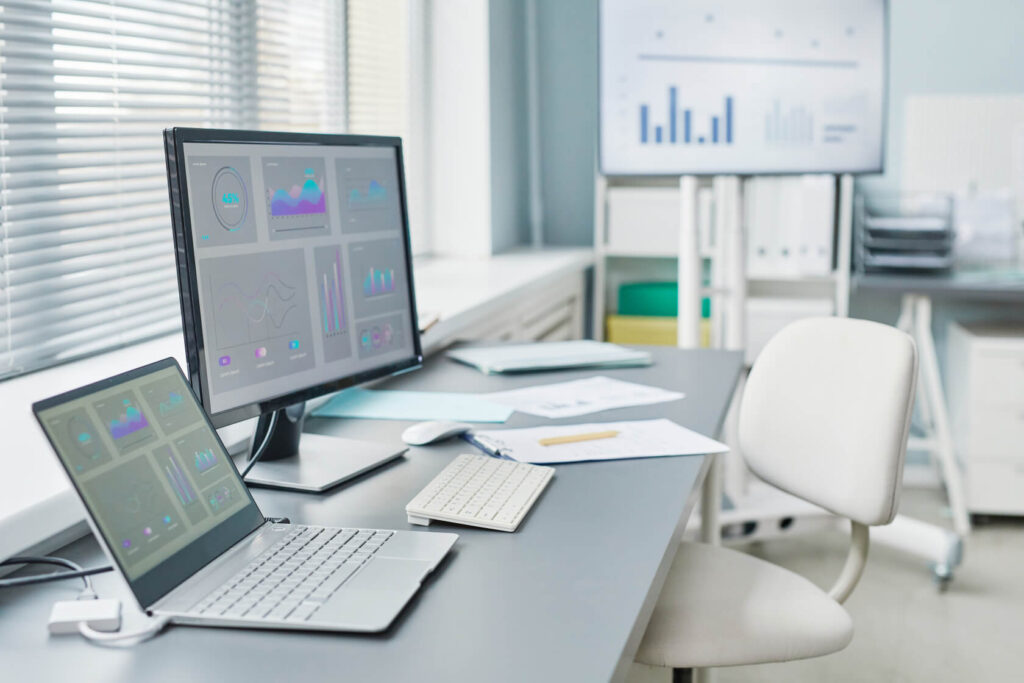 Postazione di lavoro con monitor e laptop che mostrano dashboard gestionali