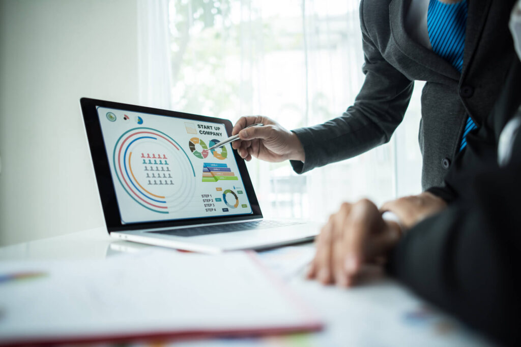 Professionista che indica grafici e dati su un laptop durante una riunione