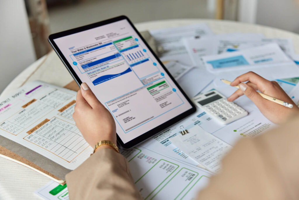 Professionista che consulta un tablet con documenti e calcolatrice sul tavolo